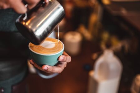 Close-up of professionally extracting coffee by barista with a pouring steamed milk into coffee cup making beautiful latte art. coffee, extraction, deep, cup, art, barista concept. の写真素材