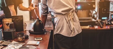 The back view of the barista in the bar counter at the coffee shop. Coffee, Barista, Bar, Cafe, deep, machine, Lifestyle concept.の写真素材