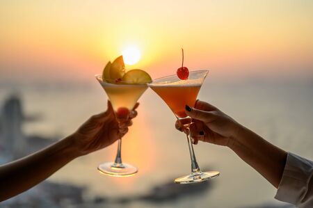 Couple enjoying of Cheers glass of cocktail in a restaurant  at sunset view sea. Cocktail, Couple, Honeymoon, Dinner, Wine, Romantic concept. の写真素材