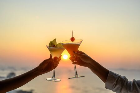 Couple enjoying of Cheers glass of cocktail in a restaurant  at sunset view sea. Cocktail, Couple, Honeymoon, Dinner, Wine, Romantic concept. の写真素材