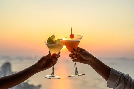 Couple enjoying of Cheers glass of cocktail in a restaurant  at sunset view sea. Cocktail, Couple, Honeymoon, Dinner, Wine, Romantic concept. の写真素材