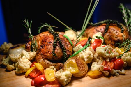 Close-up of a large turkey decorated with various vegetables around and served to a happy family on a flat wooden table. Chicken, turkey, vegetable, large, food, party, lifestyle concept.の写真素材