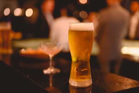 Glass of beer placed casting a shadow on the sky bar counter in restaurant. Cold beer, perfect for hang out after work. Beer, hang out, relax, restaurant, dinner concept.の写真素材