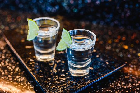 Gin or vodka with lime. Two glasses with a cocktail alcohol with lemons on the black blue surface. Vodka, cocktail, alcohol, beverage, restaurant, relax concept.の写真素材