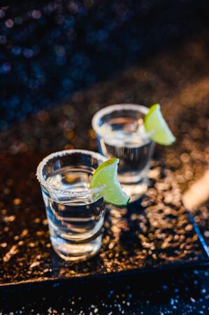 Gin or vodka with lime. Two glasses with a cocktail alcohol with lemons on the black blue surface. Vodka, cocktail, alcohol, beverage, restaurant, relax concept.の写真素材