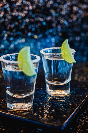 Gin or vodka with lime. Two glasses with a cocktail alcohol with lemons on the black blue surface. Vodka, cocktail, alcohol, beverage, restaurant, relax concept.の写真素材