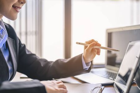 businesswoman, working, business, technology, multitasking, lifestyle concept. Businesswoman sitting to working at office desk with laptop writing something while working.の写真素材