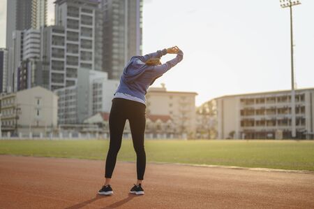 jogging, fitness, running, exercise, lifestyle, healthy concept. Young women warm up body after running jogging on the running track around the football field.の写真素材