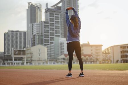 jogging, fitness, running, exercise, lifestyle, healthy concept. Young women warm up body after running jogging on the running track around the football field.の写真素材