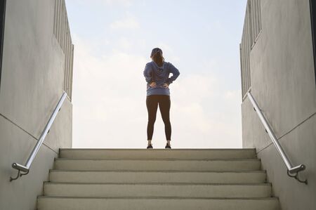 jogging, fitness, running, exercise, lifestyle, healthy concept. Rear view of young women run up the stairs on the football field in the evening.の写真素材