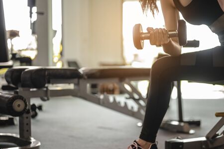 Women exercise by dumbbells at the indoor gym for good health at sunset. fitness ,workout, gym exercise ,lifestyle  and healthy concept. の写真素材