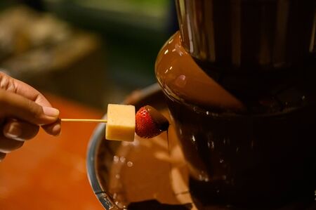 Strawberry dipping into chocolate fondue, closeup