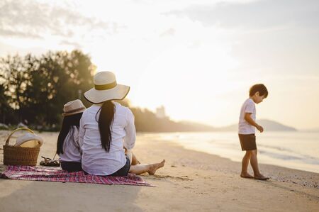 Family, travel, beach, relax, lifestyle, holiday concept. Parents and children who enjoy a picnic at the beach on sunset in holiday. の写真素材