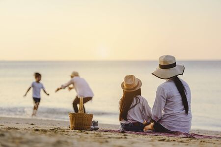 Family, travel, beach, relax, lifestyle, holiday concept. Parents and children who enjoy a picnic at the beach on sunset in holiday.の写真素材