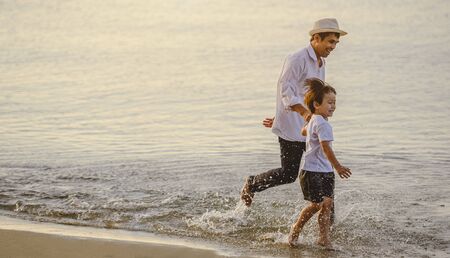 Father and his son who enjoy a picnic and sea bathing at the beach on sunset in holiday.の写真素材