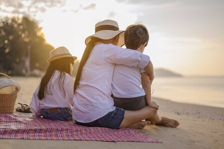 Family, travel, beach, relax, lifestyle, holiday concept. Parents and children who enjoy a picnic at the beach on sunset in holiday. の写真素材