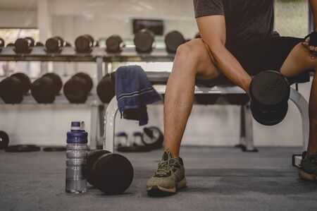 fitness, jogging, running, exercise, lifestyle and healthy concept. Young men wear sportswear, prepare dumbbell weights for exercise in the gym at sunset.の写真素材