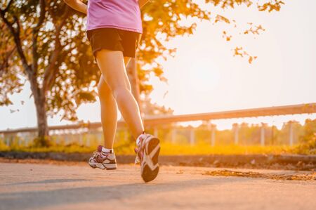 Active healthy runner jogging outdoor. Woman jogging at park in sunrise lightの写真素材
