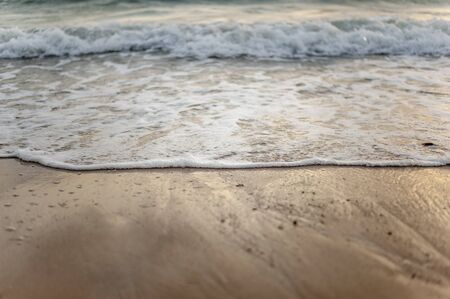 Sea, beach, sand, wave, summer, background concept. White waves on a sandy beach in the summer on sunset. Background sea concept.の写真素材