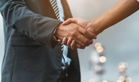 Close-up of two business partners standing and shaking hands they greeting each other during a meeting hand together is a collaborative concept of teamwork for business partners.の写真素材