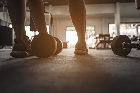 The back view of a bodybuilder exercising with a dumbbell weight at the gym. A male bodybuilder exercising with a dumbbell. Body Muscle Fitnessの写真素材