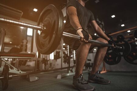 A side view of a young bodybuilder exercising in the gym, ready to lift weights, lift weights, work out all leg muscles and parts of the body.の写真素材