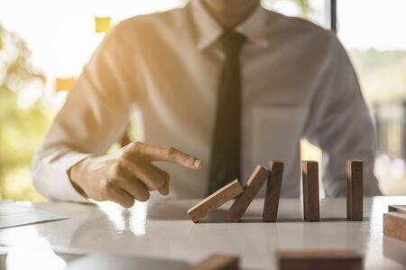 Businessman pulling or placing long wooden blocks in a modern office Indicates the impact or management risk of the business. Plan and strategy in business.の写真素材