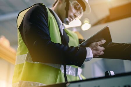 Male industrial engineers are using laptops to study about new projects in industrial plants. He acted happily and professionally. Engineering and architecture technology for factory industry concept.の写真素材