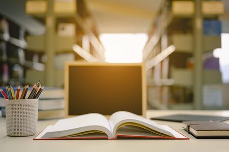 Opened book with pencil box and blackboard on the desk wood in the library prepare for new knowledge.  Education background concept.の写真素材