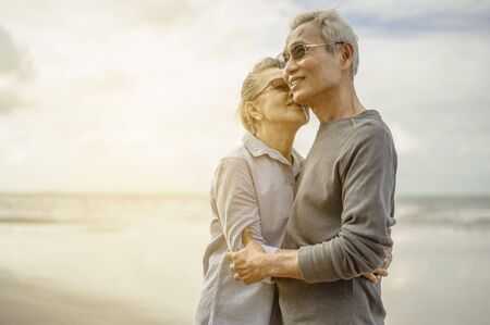 Senior lovers hug and kiss each other in the sunset on the beach Plan life insurance with a happy retirement concept.の写真素材