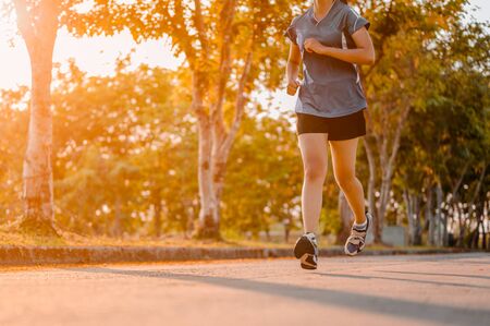 Active healthy runner jogging outdoor. Woman jogging at park in sunrise lightの写真素材