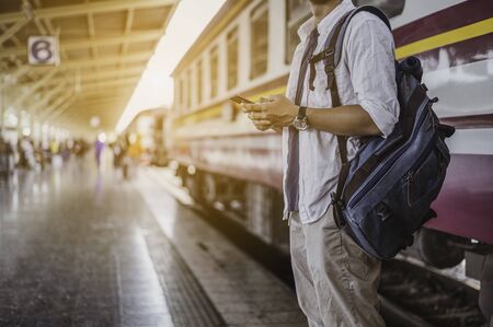 Man with mobile phone and bag waiting for train.Work and travel concept.の写真素材