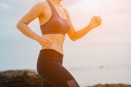 fitness woman jogging at sunset in the beach.の写真素材