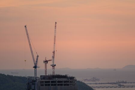 Cranes are building blocks along the coast at sunset.
Construction using a crane at sunset on the pier.Crane constructionの写真素材