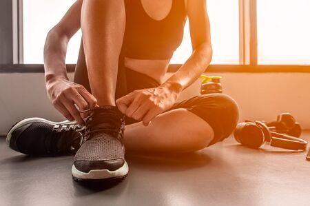  woman tying shoelaces at gym.の写真素材