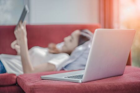 Happy young woman with tablet laying on sofa and  have a laptop.の写真素材