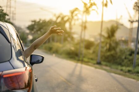 Happy woman Driving on Country Road into the Sunsetの写真素材