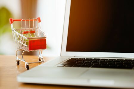 shopping concept - Empty Shopping Cart, laptop, on rustic wooden background.の写真素材