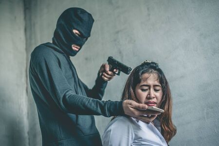 bandit with masked holding gun to Business woman tied.rope hostage concept.の写真素材