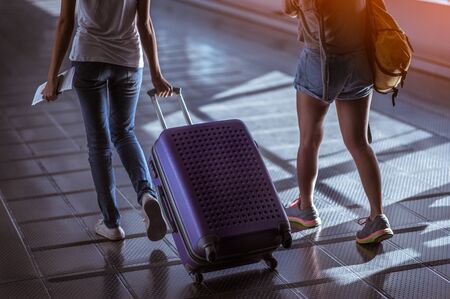 Young woman pulling suitcase in modern airport terminal. Travelling guy with his luggage while waiting for transport. Rear view. Copy spaceの写真素材