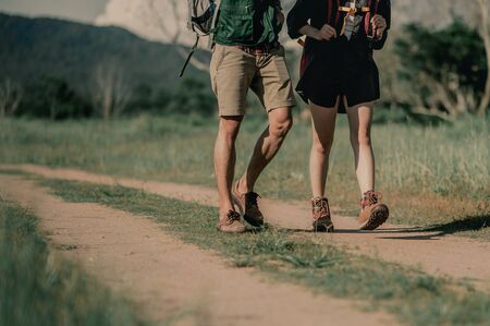 Hikers with backpacks walking trough forest path wearing mountain boots with focus on the shoes.