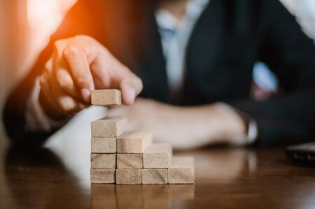 plan and strategy in business.risk concept.hand of man has piling up and stacking a wooden block.Businessman Building The Success.の写真素材