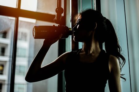 The sports young woman drinks protein in a shaker in a gym. Sports 
の写真素材