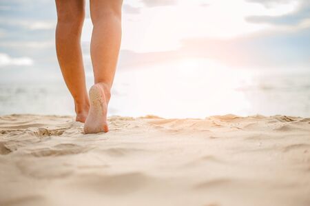 Woman walking on the beach at sunset.の写真素材