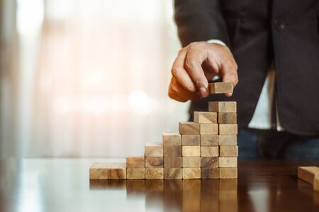 plan and strategy in business.risk concept.hand of man has piling up and stacking a wooden block.Businessman Building The Success.の写真素材