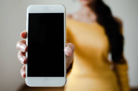 image of hand holding white mobile phone with blank black screenの写真素材