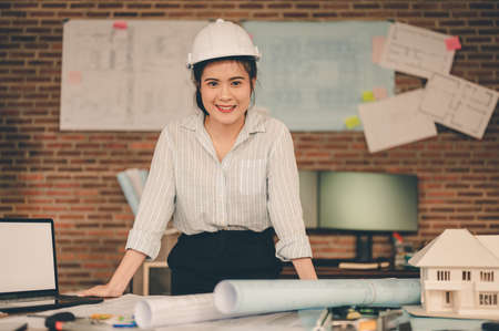 Female architect are holding on blueprint and wear a helmet working engineering or architecture project. Engineer, Engineering, Architecture, Blueprint, Planning, Occupation concept.の写真素材
