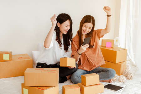 Young woman asian work from home talking with customers to sell products online and delivery for customer. Business owner, SME, shipping, work from home(WFH), freelance, Start up concept.の写真素材