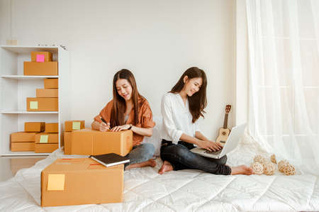 Young woman asian work from home talking with customers to sell products online and delivery for customer. Business owner, SME, shipping, work from home(WFH), freelance, Start up concept.の写真素材
