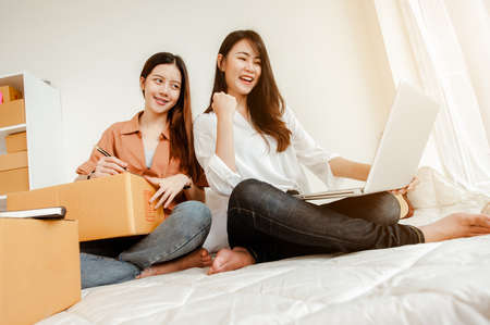 Young woman asian work from home talking with customers to sell products online and delivery for customer. Business owner, SME, shipping, work from home(WFH), freelance, Start up concept.の写真素材